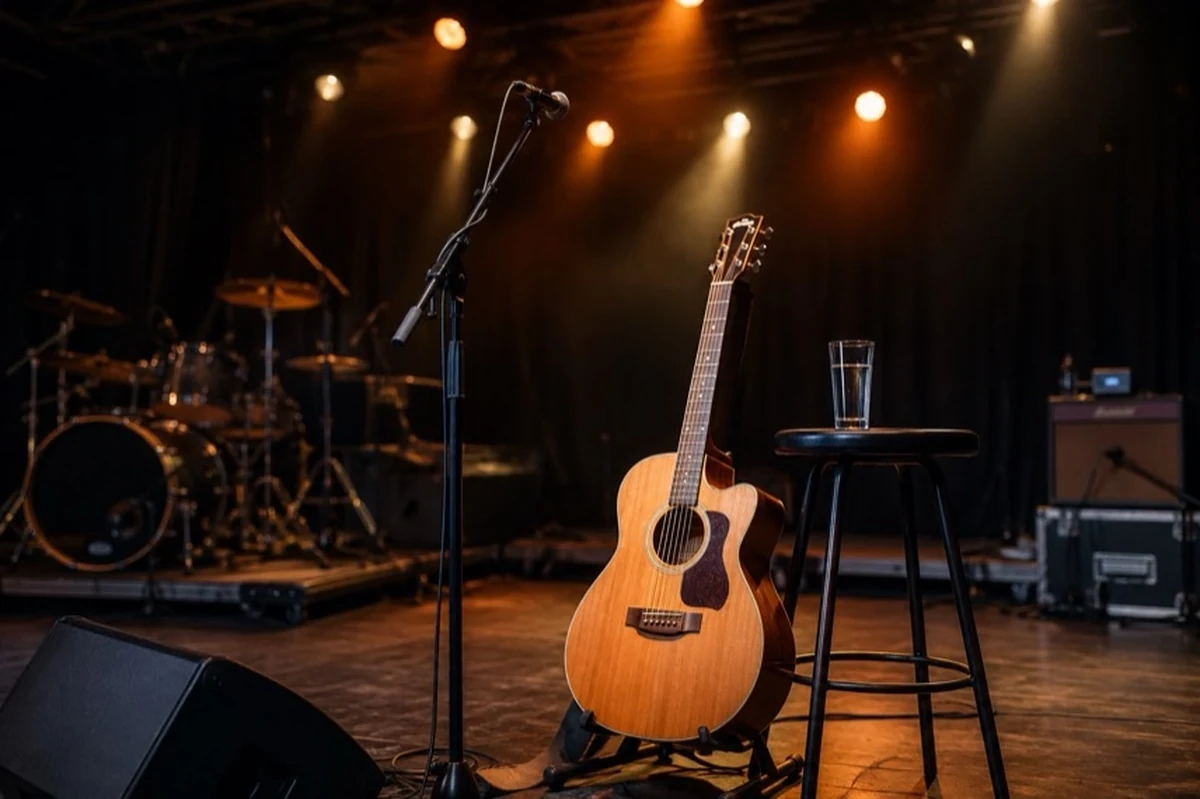 Leere Konzertbühne mit Mikrofon, Akustikgitarre und warmem Bühnenlicht in einem Veranstaltungssaal.