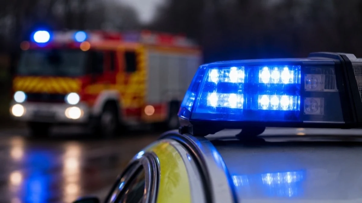 Feuerwehr- und Polizeifahrzeug mit Blaulicht und Absperrband auf einer neutralen Fläche