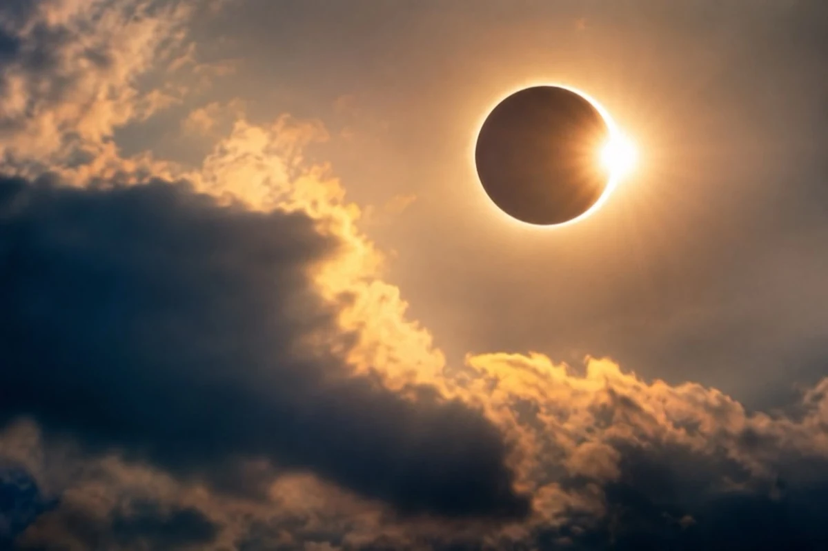 Partielle Sonnenfinsternis über einer dunklen Hügellandschaft bei tief stehender Abendsonne.
