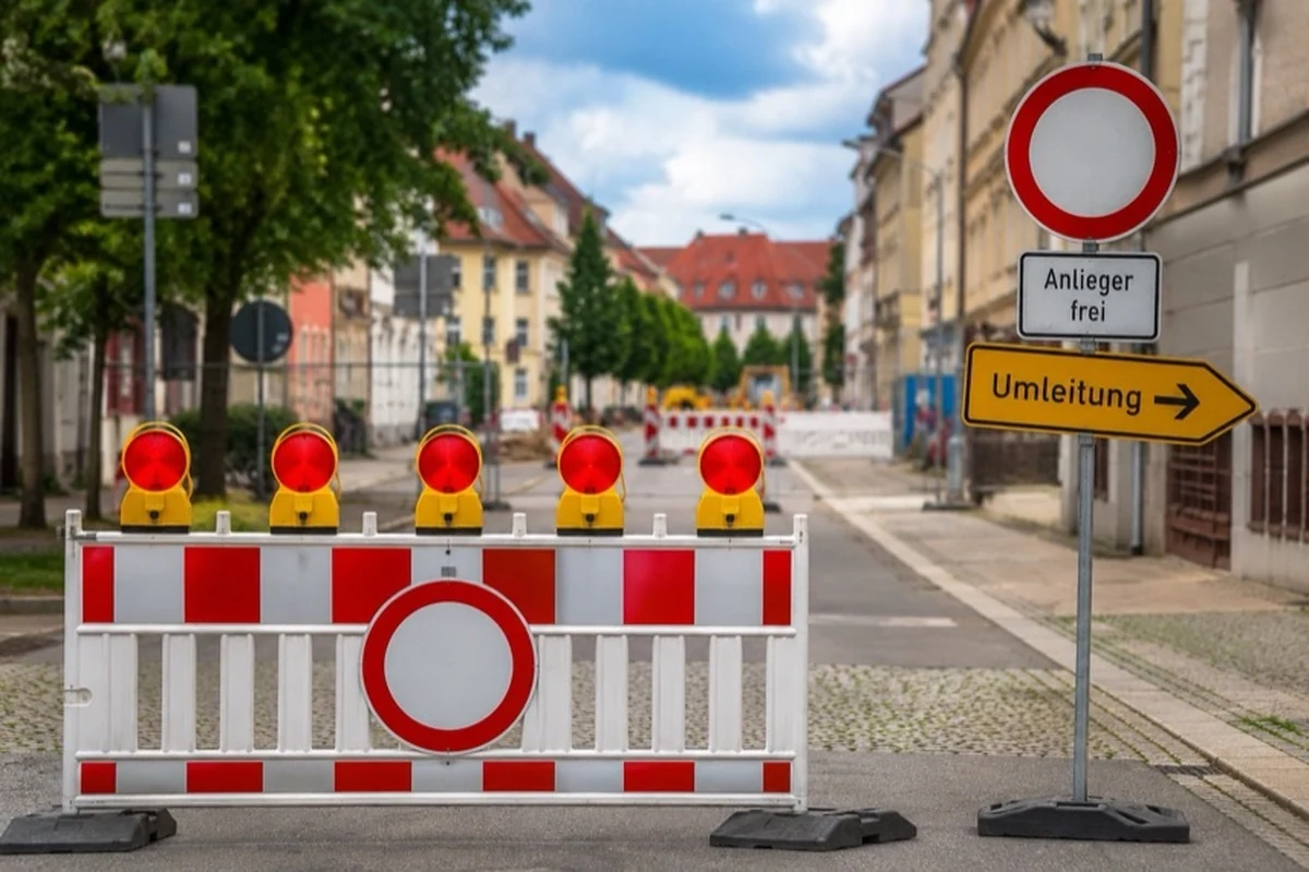 Eine innerstädtische Straße mit Baustellenbaken, Verkehrsschildern und einem abgesperrten Fahrbahnbereich.