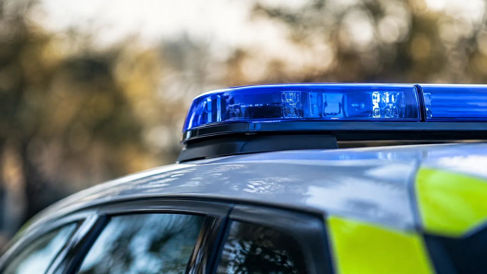 Blaues Signallicht auf dem Dach eines Polizeifahrzeugs vor unscharfem Hintergrund ohne erkennbare Personen oder Kennzeichen.