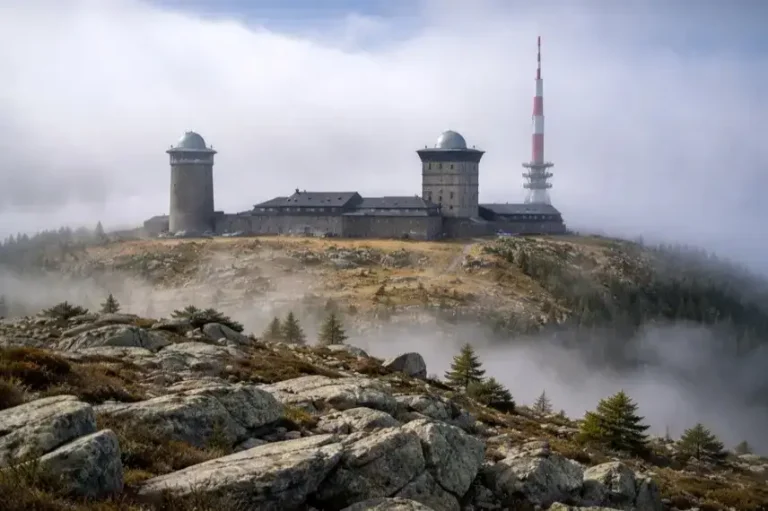 Brockengipfel im Harz mit Gebäuden auf dem Plateau, umgeben von Nebel und felsiger Landschaft