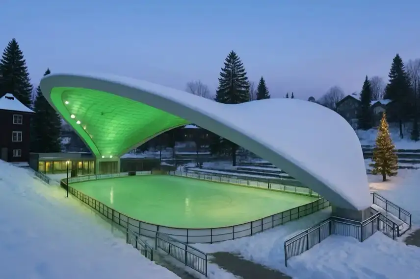 Winterliche Eisfläche in einer leeren, hell beleuchteten Arena mit Schneeresten an den Holzelementen, ohne Menschen oder erkennbare Details.