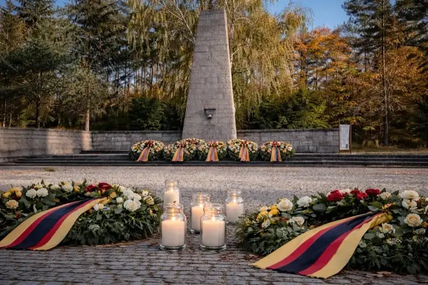 Mahnmal der Gedenkstätte Langenstein-Zwieberge mit brennenden Kerzen und Kränzen an einem winterlichen Tag.